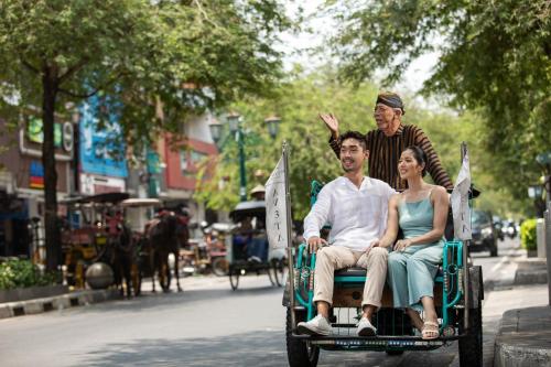 a man and a woman riding in a horse drawn carriage at Aveta Hotel Malioboro in Yogyakarta