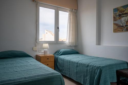a bedroom with two beds and a window at AT177 Pins, dúplex en 1ra línea, con piscina, airco in Torredembarra