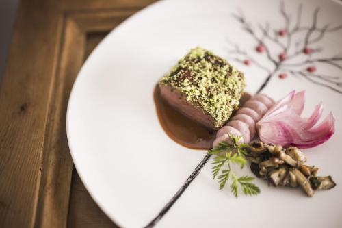 a plate of food with a piece of cake and flowers at Boutique Pension Erlacher - Adults Only in Villandro