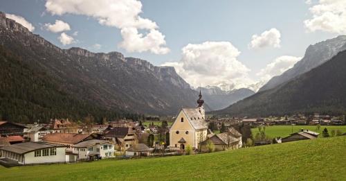 a small village with a church in the mountains at Alpegg Chalets in Waidring
