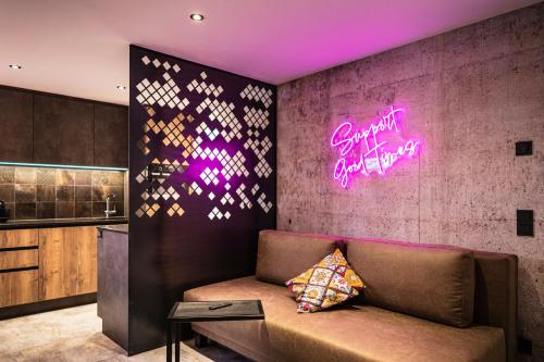 a couch in a room with a neon sign on the wall at PHILSON Apartments in Saalbach Hinterglemm