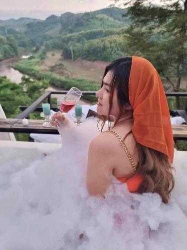 a woman in a wedding dress holding a glass of wine at Doi Sang Farm Stay - ดอยซางฟาร์มสเตย์ in Ban Huai Kom