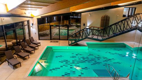 a pool in a room with chairs and a staircase at Spa & Wellness Hotel Fitak**** in Liptovský Ján