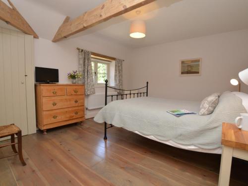 a bedroom with a bed and a dresser with a television at 3 Bed in Sherborne COWOB in Haselbury Bryan