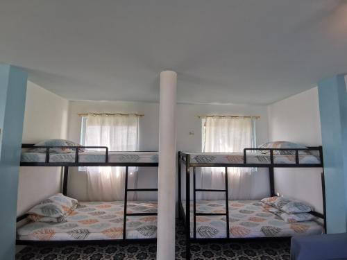 two bunk beds in a room with two windows at OCEANO CON VISTA HIGHLAND in Tagbaobo