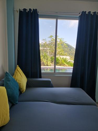 a bedroom with a bed with blue curtains and a window at OCEANO CON VISTA HIGHLAND in Tagbaobo
