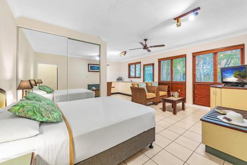 um quarto com uma cama e uma sala de estar em Bay Village Tropical Retreat & Apartments em Cairns