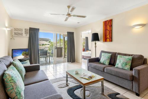 Bay Village Tropical Retreat & Apartments في كيرنز: غرفة معيشة مع أريكة وطاولة
