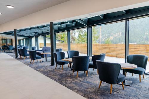 a waiting room with tables and chairs and windows at Spa & Wellness Hotel Fitak**** in Liptovský Ján