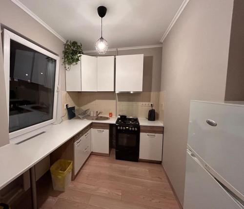 a kitchen with white cabinets and a black stove at Cozy apartment close to Riga Airport in Rīga