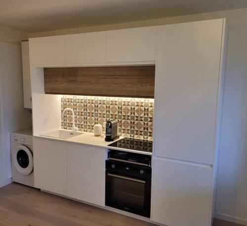 a kitchen with white cabinets and a stove at Le Verdi - Les Gîtes de la Côte d'Amour in Le Croisic