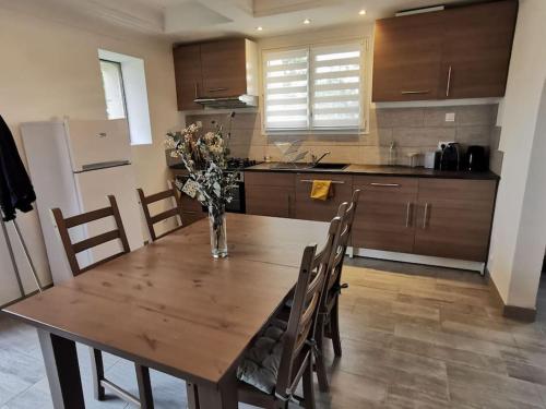 a kitchen with a wooden table with chairs and a refrigerator at Maisonnette rénovée et son jardin in Châtellerault