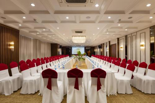 a banquet hall with white tables and red chairs at Daphovina Hotel in Nha Trang