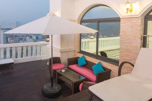 a balcony with a white umbrella and a table and chairs at Daphovina Hotel in Nha Trang
