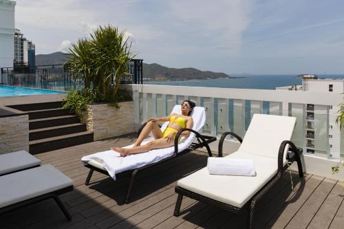 a woman sitting in a chair on a balcony at Daphovina Hotel in Nha Trang
