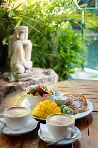 a wooden table with two cups of coffee and food at Bay Village Tropical Retreat & Apartments in Cairns