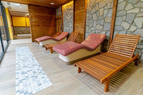 a row of wooden chairs in a room with a stone wall at Spa & Wellness Hotel Fitak**** in Liptovský Ján