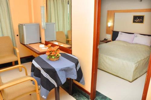 HOTEL CALICUT GATE في Ferokh: غرفة صغيرة مع سرير وطاولة مع منضدة sidx