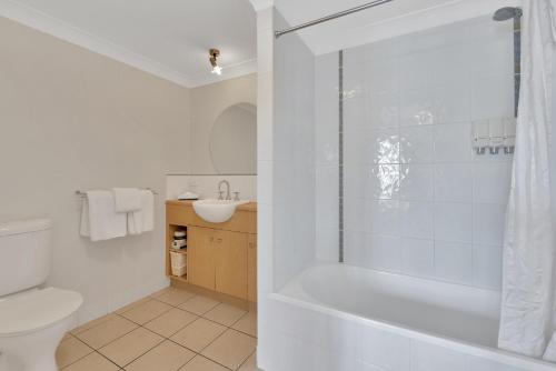 a bathroom with a tub and a toilet and a sink at Bay Village Tropical Retreat & Apartments in Cairns