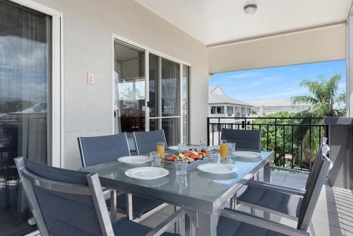 a dining room table with chairs and a table with fruit on it at Bay Village Tropical Retreat & Apartments in Cairns