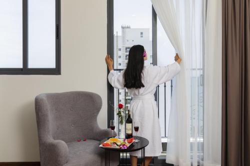 a woman is looking out of a window at Daphovina Hotel in Nha Trang