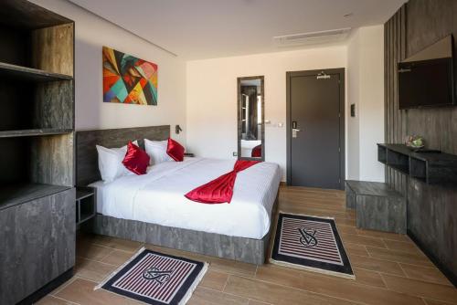 ein Schlafzimmer mit einem großen weißen Bett mit roten Kissen in der Unterkunft coast hotel in Boumerdes