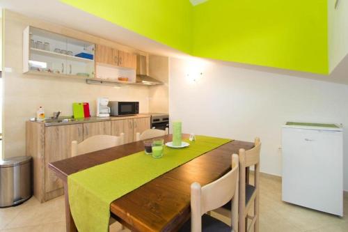 a kitchen with a wooden table with chairs and a refrigerator at Villa Patricija-apartmani in Poreč