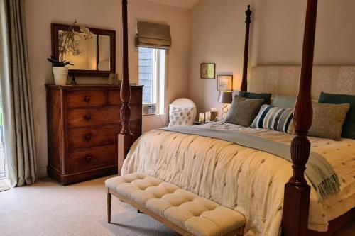 a bedroom with a bed with a dresser and a mirror at Luxury 4 poster lakefront rural retreat in Heckfield