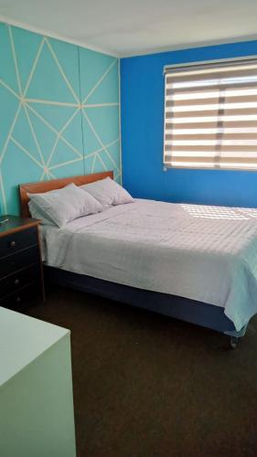 a blue bedroom with a bed and a window at Casa Her Pto Montt 3Dorm in Llanquihue