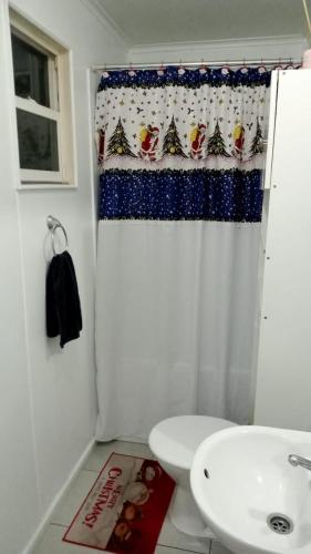 a bathroom with a christmas shower curtain next to a toilet at Casa Her Pto Montt 3Dorm in Llanquihue