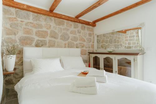 a bedroom with a white bed and a stone wall at Casa di Pietra in Kotor