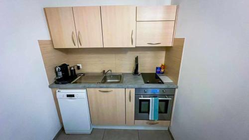 uma pequena cozinha com um lavatório e um fogão em Studio avec kitchenette tout équipée em Porrentruy