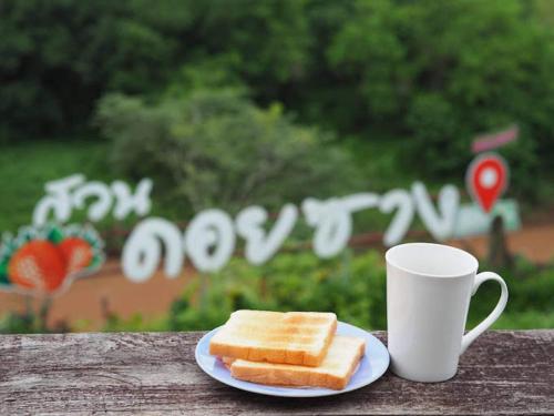 a plate with two slices of bread next to a coffee cup at Doi Sang Farm Stay - ดอยซางฟาร์มสเตย์ in Ban Huai Kom