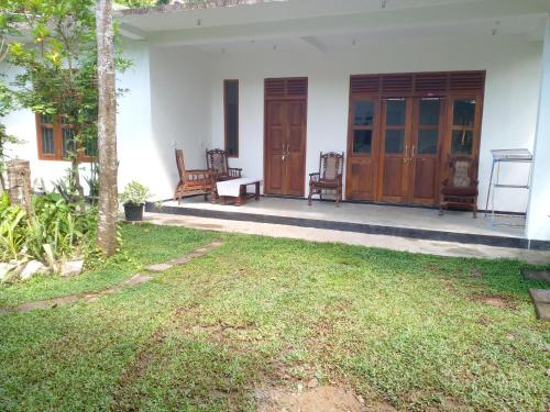 a white house with two chairs and a yard at Villa Ameliya in Unawatuna