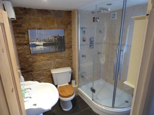 a bathroom with a shower and a toilet and a sink at Church Street Cottage in Staithes