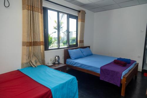 2 Betten in einem Zimmer mit Fenster in der Unterkunft Absolute Breeze by cherins in Matara