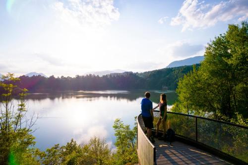 a man and woman standing on a bridge overlooking a lake at Landhaus BERGSEE in Bodensdorf