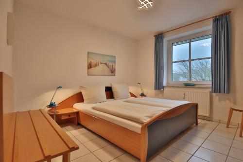 Schlafzimmer mit einem Bett, einem Tisch und einem Fenster in der Unterkunft Maison Baltique Niendorf Maison Baltique Appartement 15 in Häven