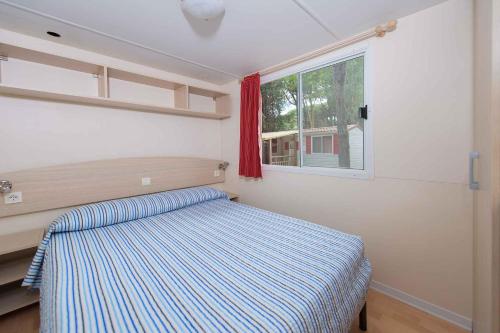 a small bedroom with a bed and a window at Mobilehomes in Lido di Spina 21308 in Lido di Spina