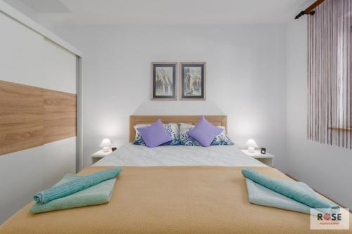 1 dormitorio con 1 cama grande con almohadas azules y moradas en Apartmani Nataša, en Vrsar