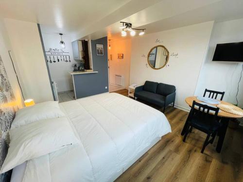 une chambre avec un grand lit blanc et une table dans l'établissement Studio Chez Sissi - hypercentre -, à Honfleur