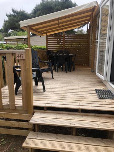 a wooden deck with chairs and an umbrella at Mobilhome 4 etoiles in Narbonne