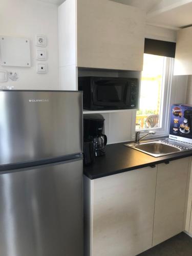 eine Küche mit einem Kühlschrank aus Edelstahl und einer Spüle in der Unterkunft Mobilhome 4 etoiles in Narbonne