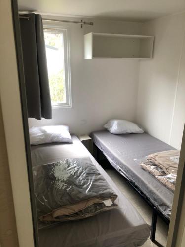 two beds in a small room with a window at Mobilhome 4 etoiles in Narbonne