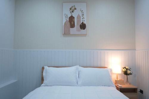 um quarto com uma cama com lençóis brancos e um candeeiro em Room61-รูม61 em Phuket
