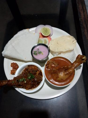 a plate of food with meat and dip and bread at Anant Villa & Resorts in Nagaon