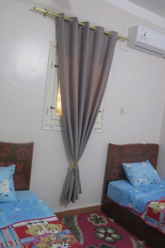 a bedroom with two beds and a window with a curtain at Seashell in Quseir