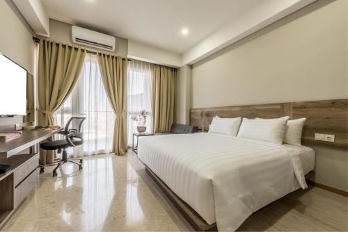 a bedroom with a large white bed and a desk at Grande Valore Hotel Cikarang in Cikarang