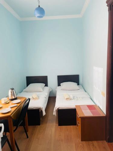 two beds in a room with a table and a desk at Villa Jakos Paradise in Batumi