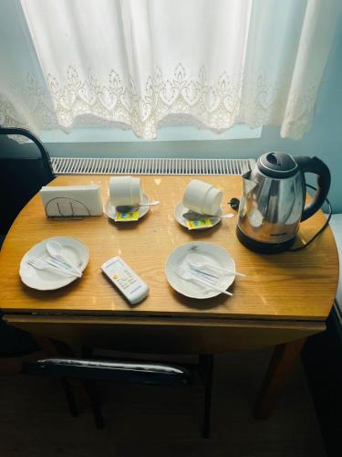 a wooden table with a tea pot and plates and a phone at Villa Jakos Paradise in Batumi